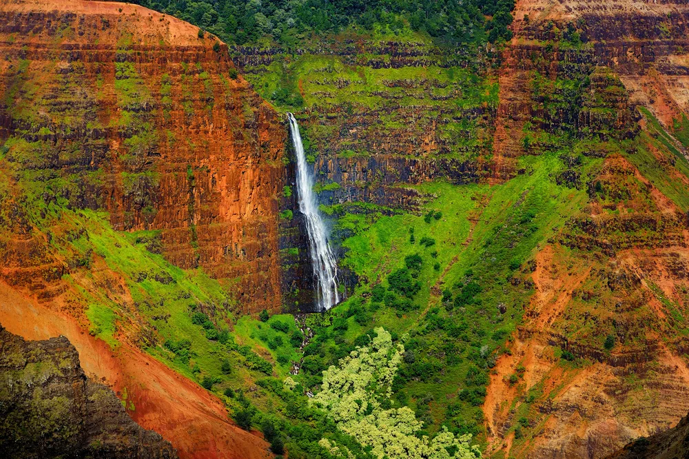 Stunning view of the waterfall in Waimea State Park, as seen from the red clay soil above