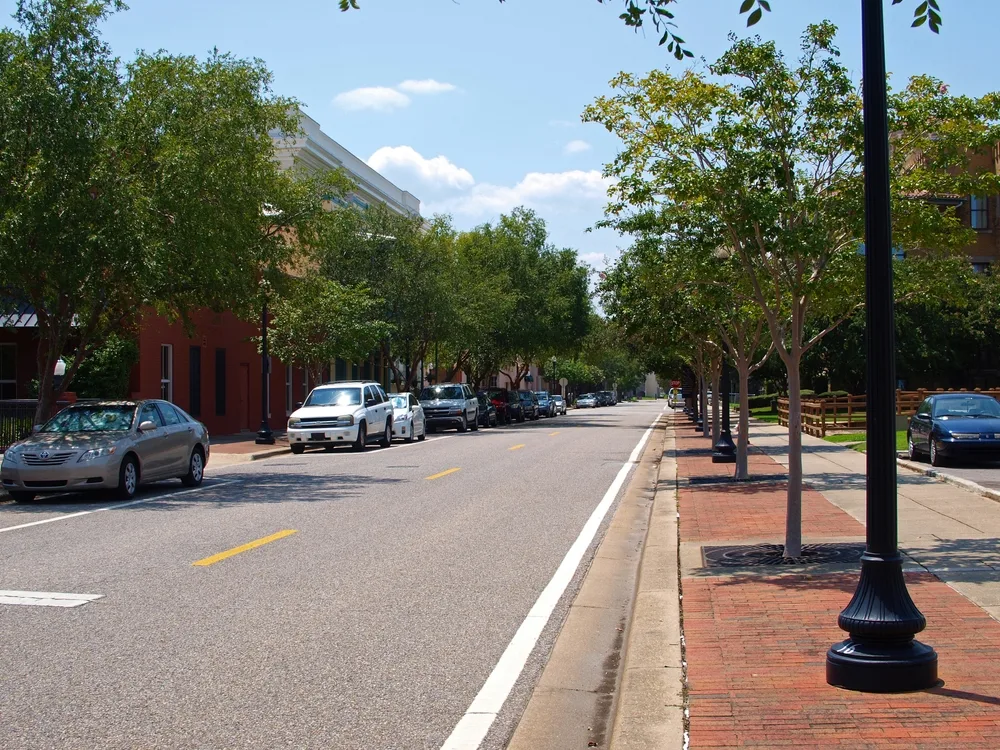 Photo of an empty street with hardly anyone on it with cars parked on either side pictured during the cheapest time to visit Pensacola