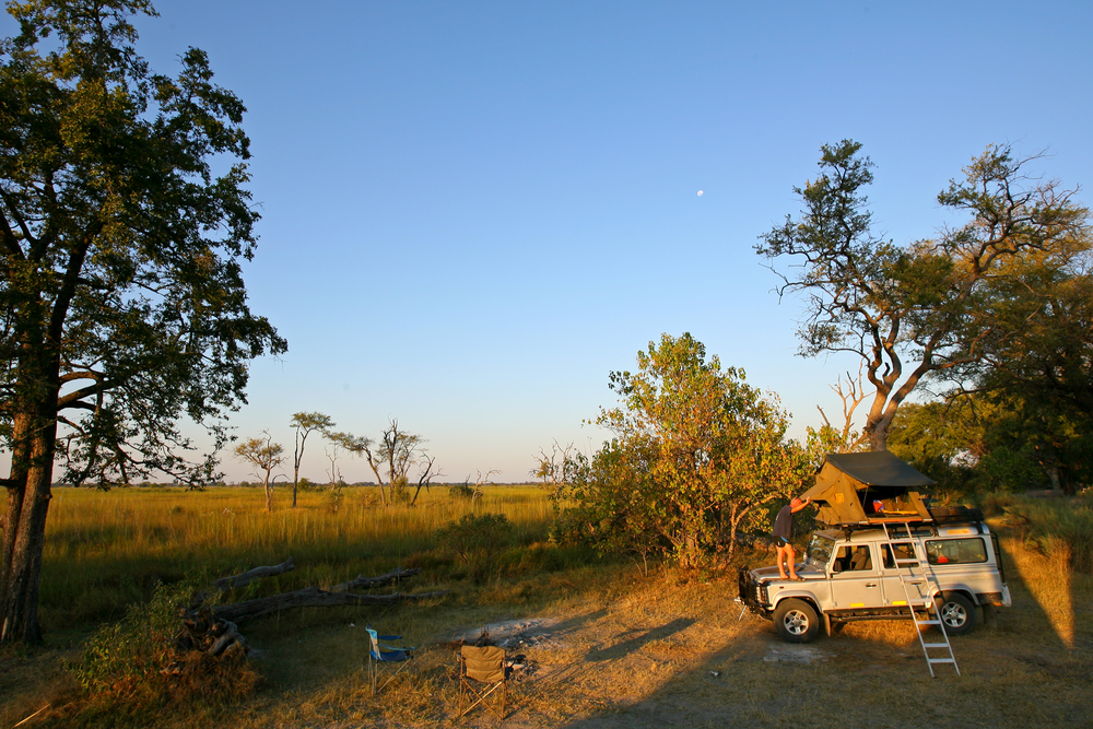 Moremi Game Reserve with man setting up camp with his rented vehicle shows the cheapest African safari cost