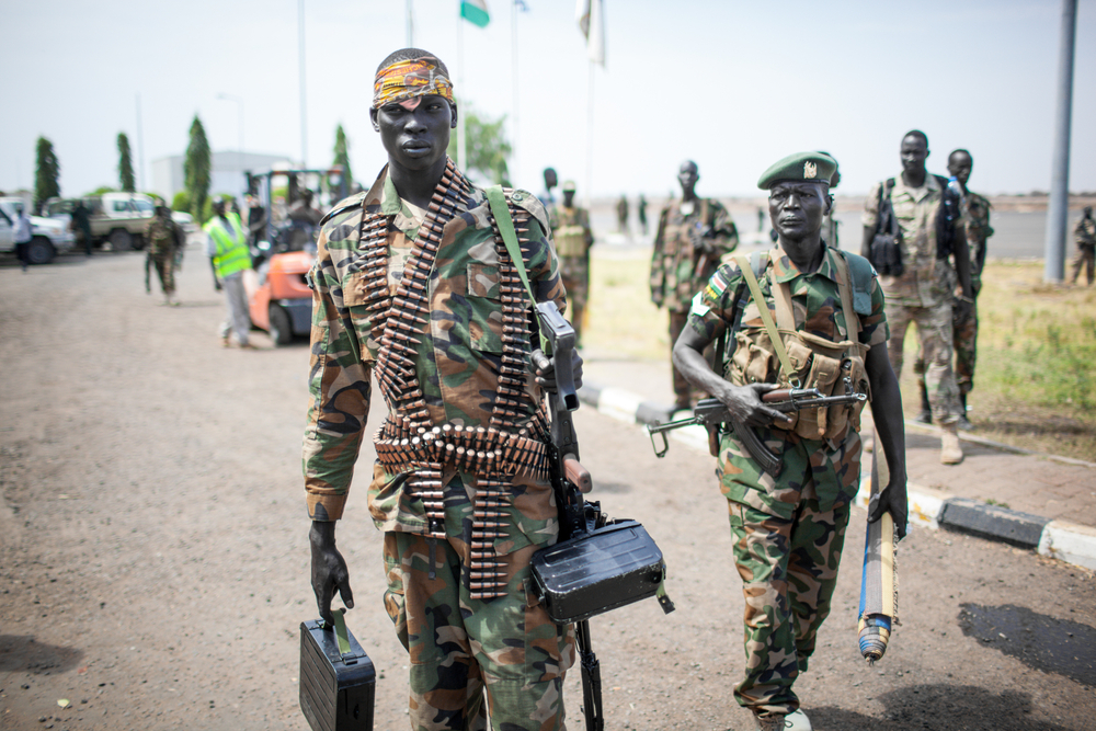 Two Sudanese soldiers wearing camouflage and bullet vests holding weapons 