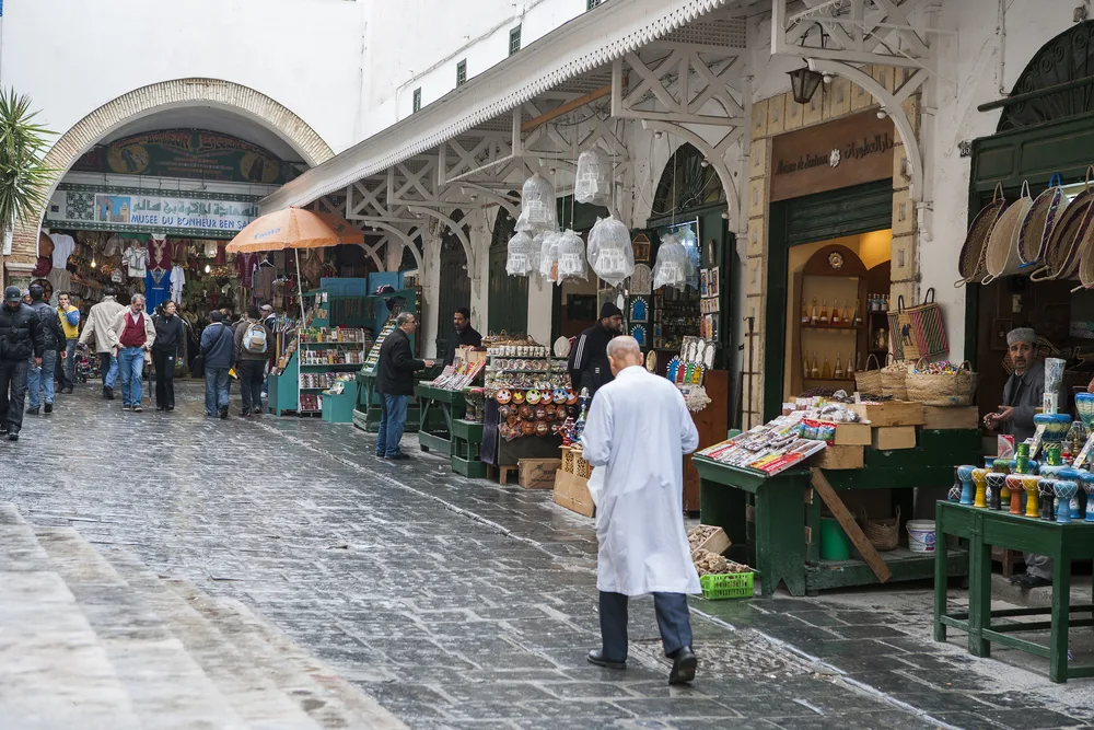 Neat open-air market in Tunis pictured with people walking along the semi-rainy streets