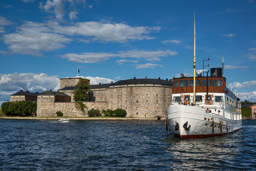 Old wooden steamer pulling away from the Vaxholm Fortress on the Stockholm Archipelago, one of the must-see places in Sweden