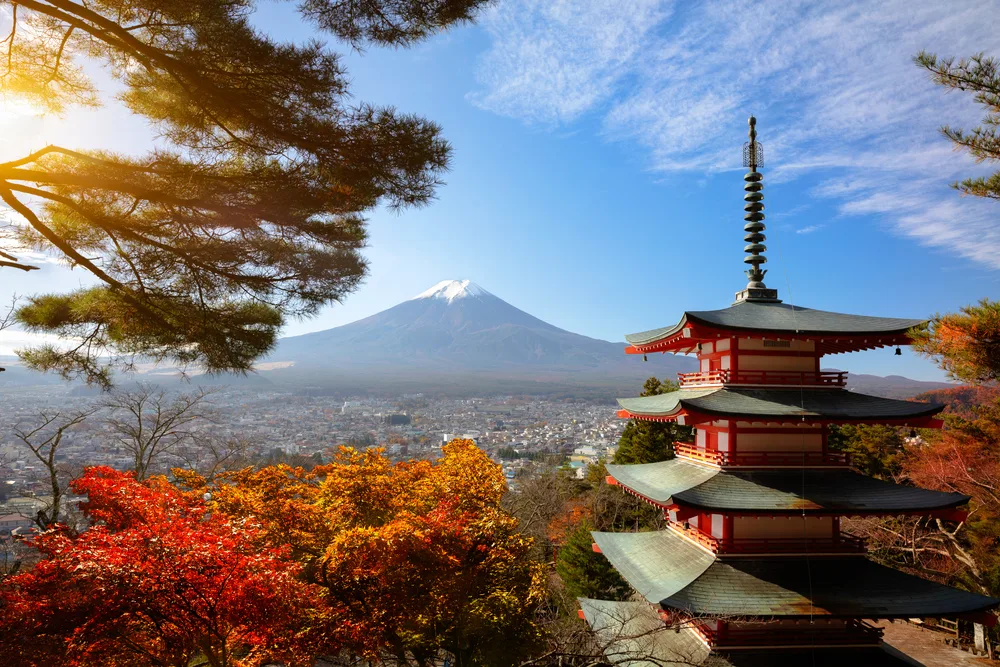 Red leaves as seen in autumn pictured during the fall with Mount Fuji in the background and a temple on the right in Tokyo, one of the best places to visit in September