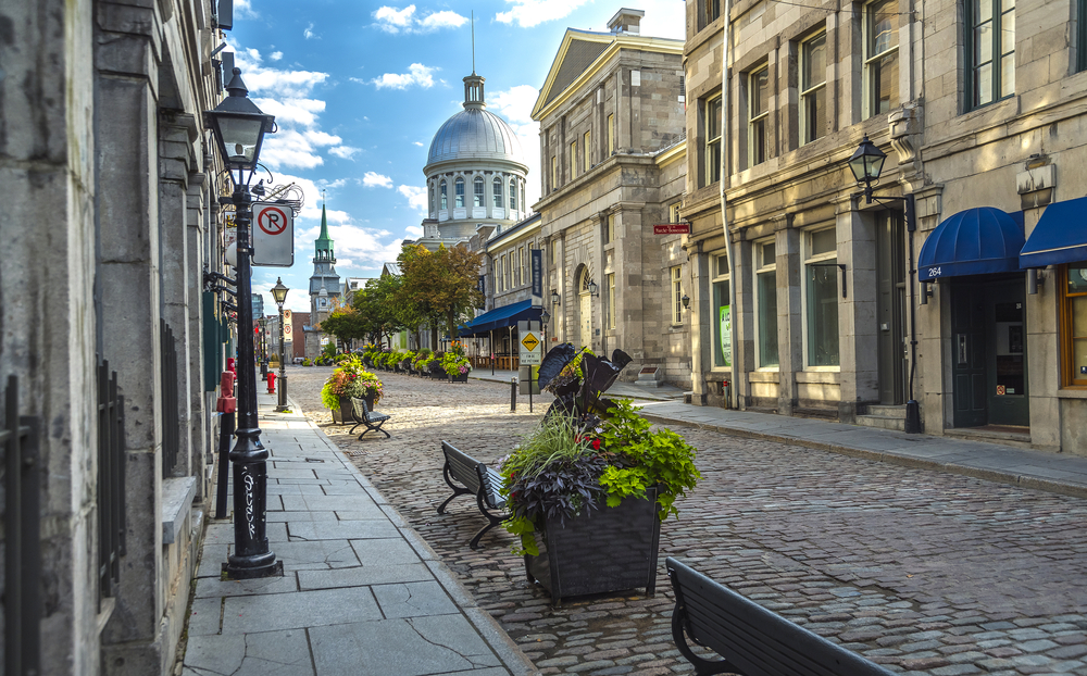 Photo of the courthouse building behind a cobblestone street on a clear day during the month of August in Montreal