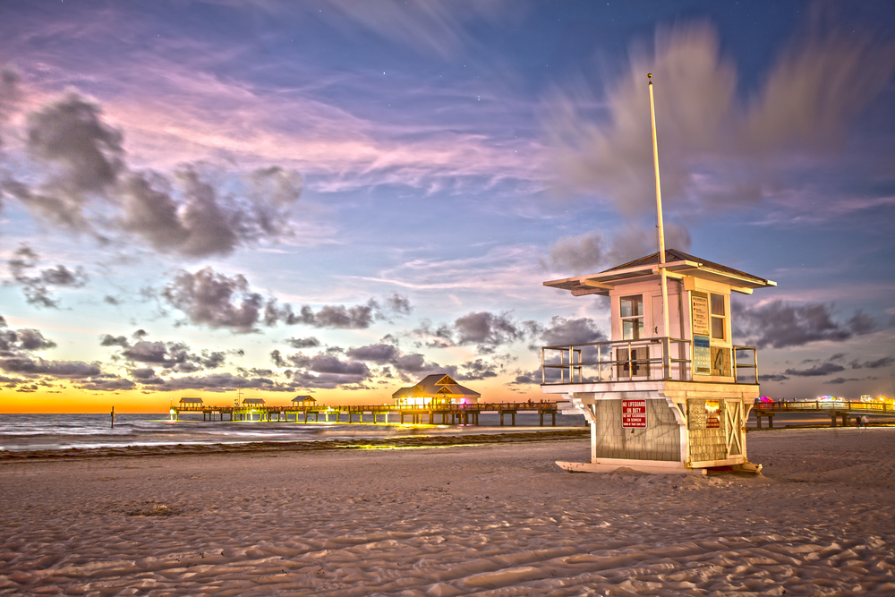 Sunset over the brown sand and lifeguard stand pictured during the best time to go to Clearwater