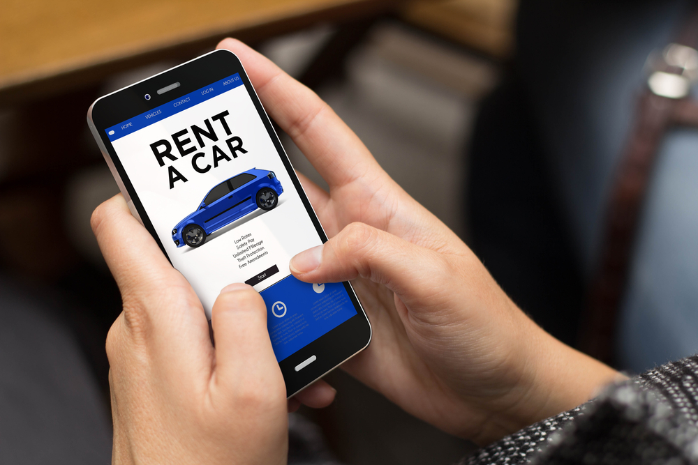 Hands holding a smartphone using a car rental app showing how to rent a car without a credit card