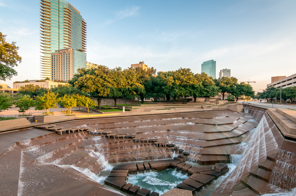 The Texas Water Gardens pictured with water flowing into several hexagonal structures with a clear sky in the background for a piece on the best places to go to while in Texas