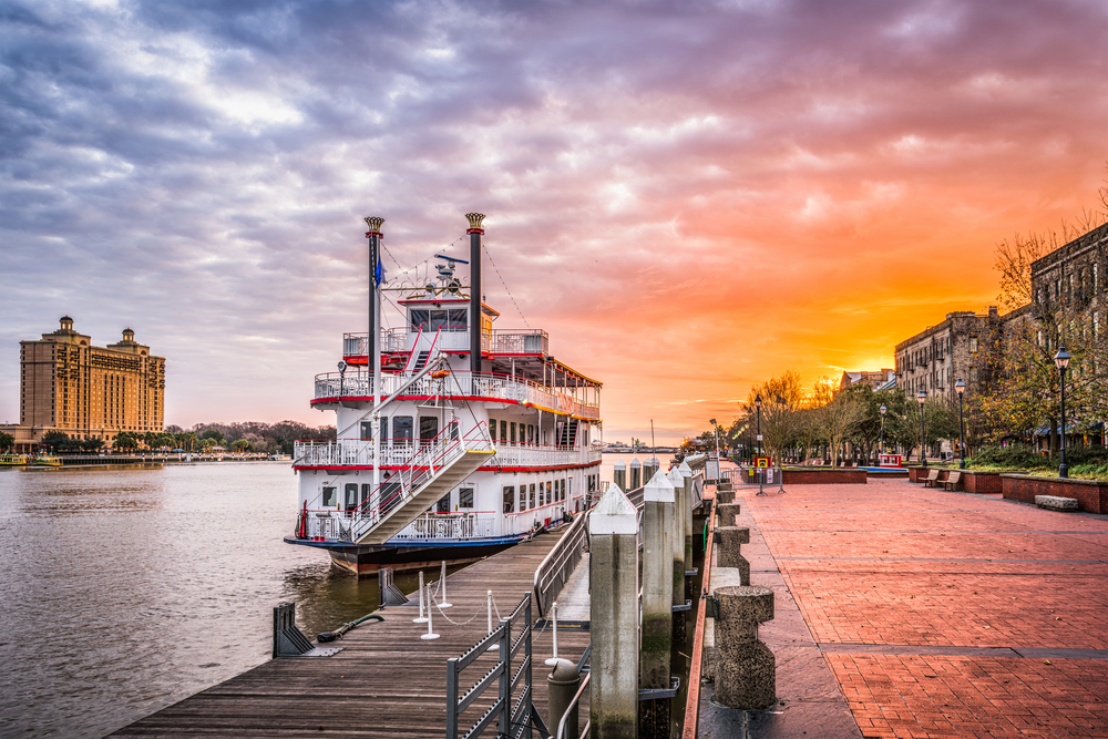 Riverboat cruiser docked next to the boardwalk in Savannah, Georgia, one of the best places to visit in April, seen at dusk