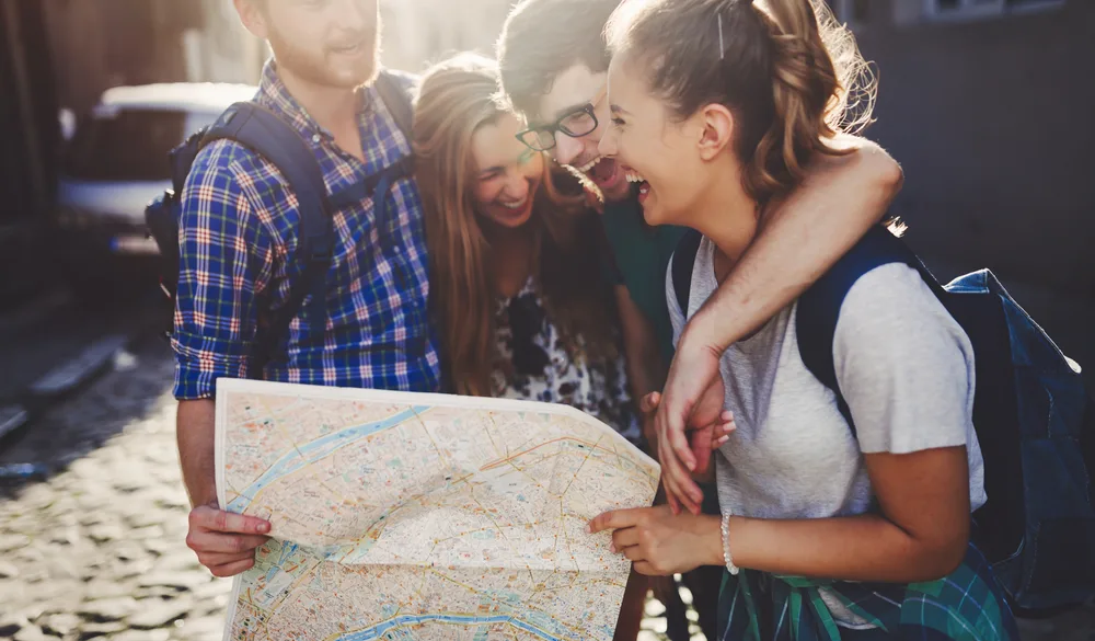 Group of friends holding a map and uncontrollably laughing