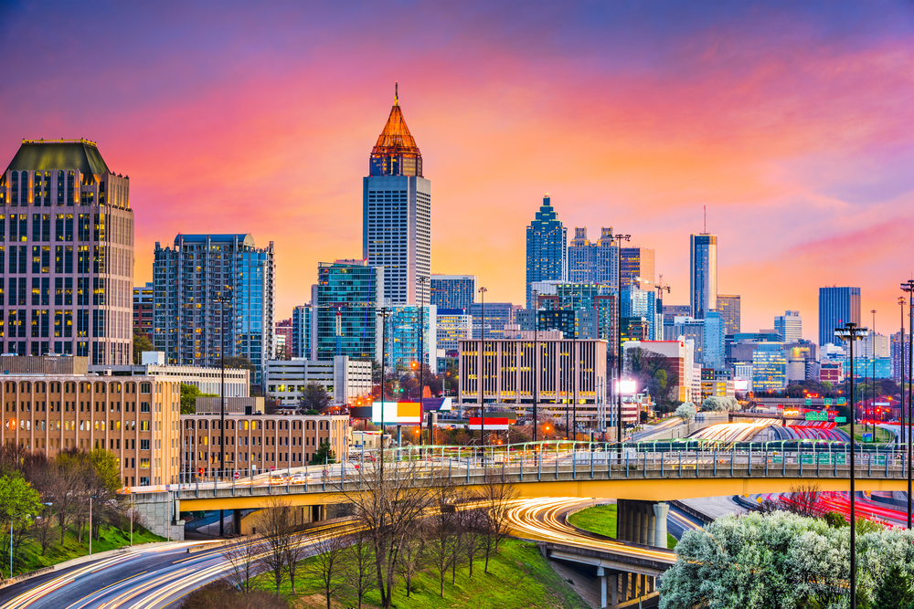 Skyline of downtown Atlanta pictured at dusk with traffic flying by in a low-exposure image