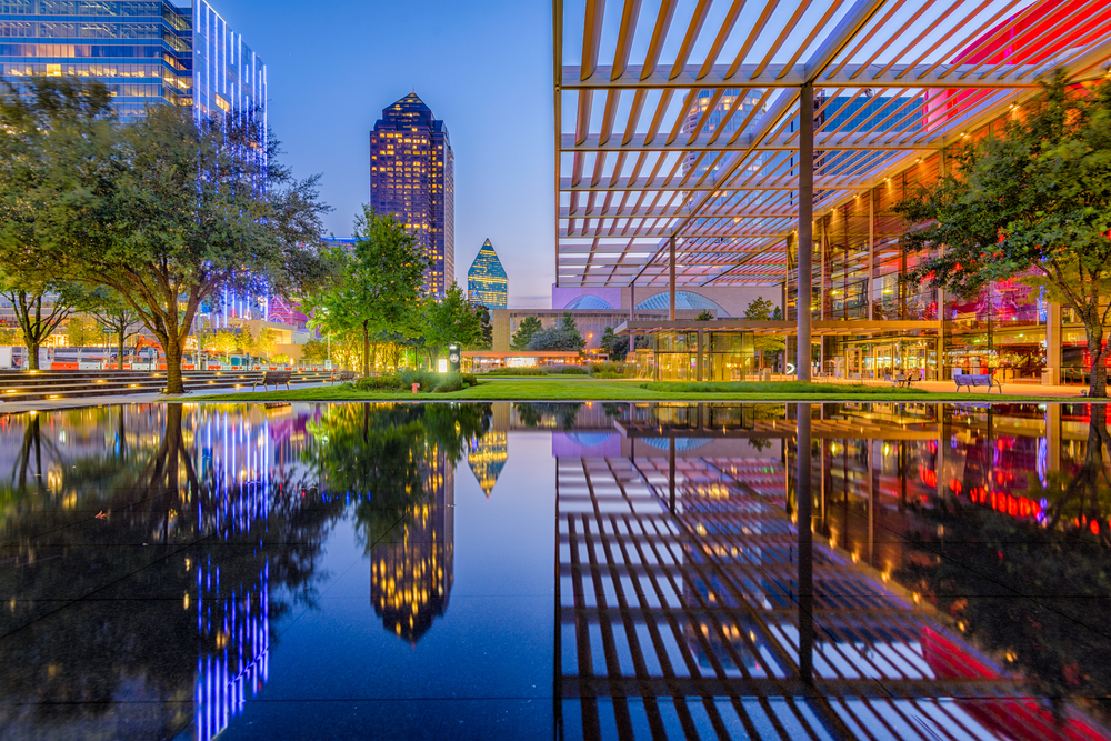 Metal pergola towering over a reflecting pond with tall buildings overlooking the scene in downtown Dallas, one of the best places to visit in Texas
