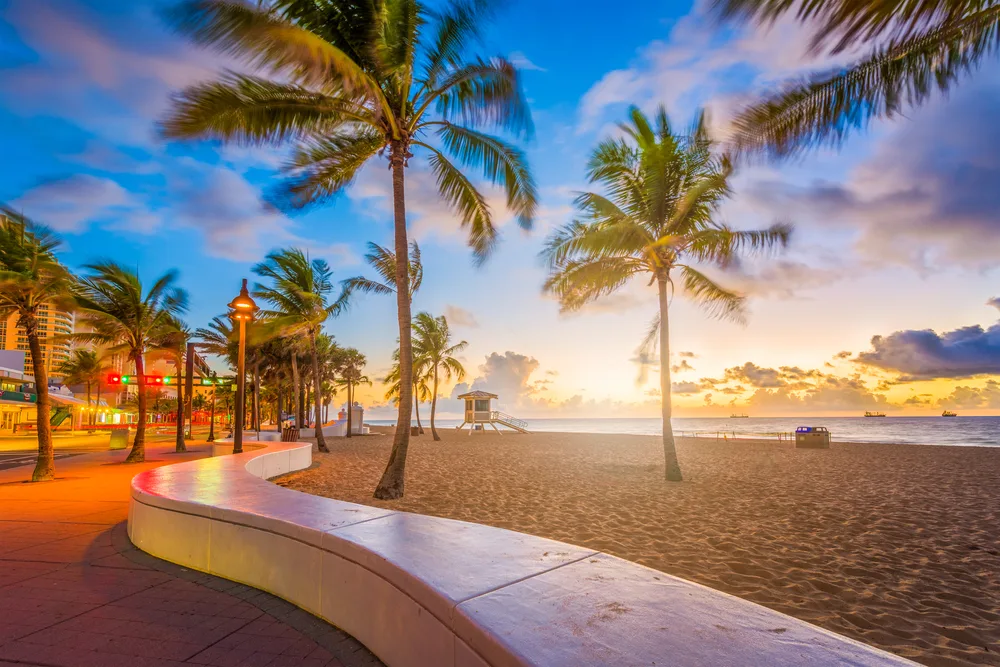 Winding concrete path alongside the beach and palm trees in Fort Lauderdale, one of our top picks for places to visit in Florida for couples, as seen at dusk