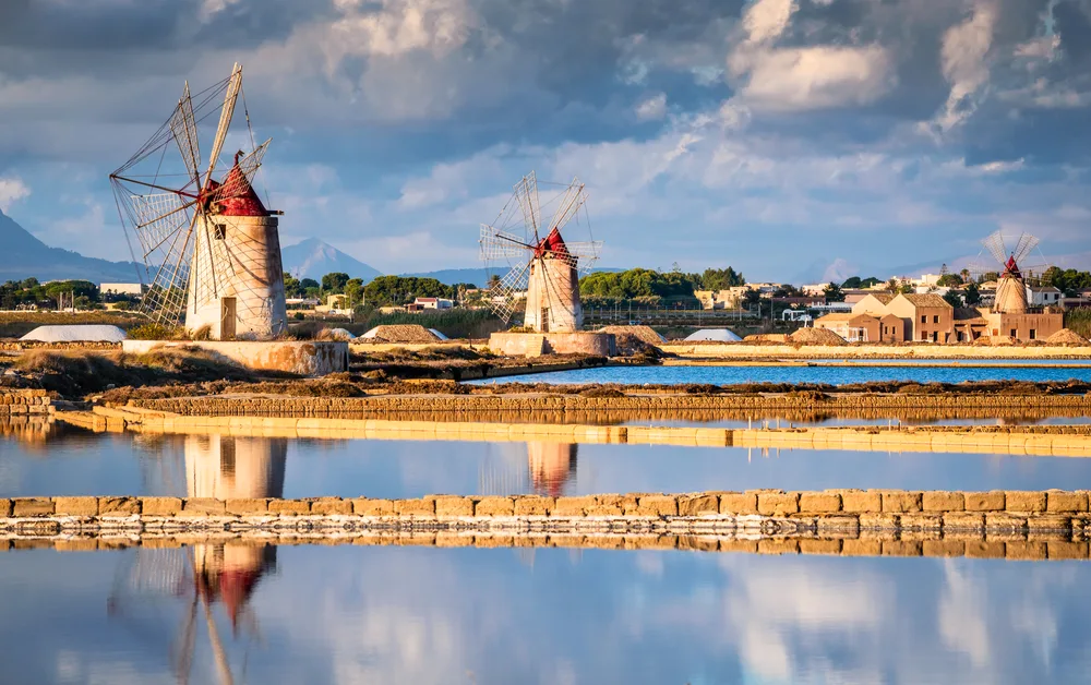 Windmills in the Marsala region of Sicily pictured on a clear day with still water around the structures