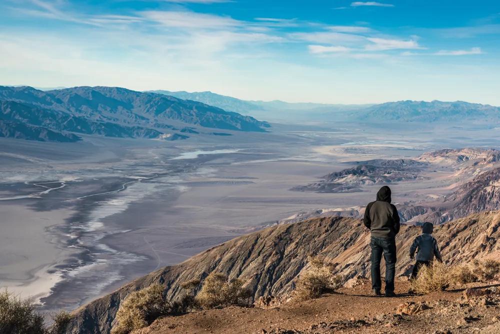 Man and his son standing on the edge of a cliff overlooking a valley below, pictured as one of the best places to visit in December