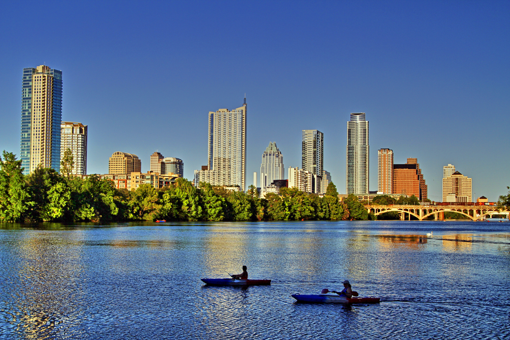 Two people kayaking on Lady Bird Lake pictured on a clear, blue-sky day for a piece on the best places to visit in Texas