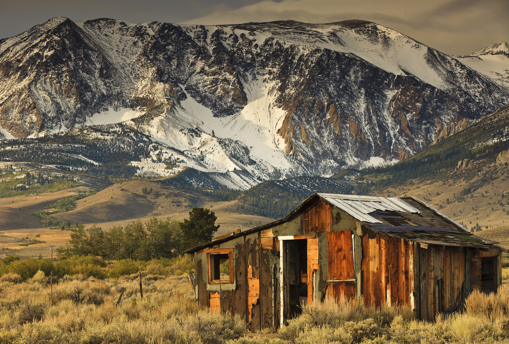 Lone wooden cabin pictured on a clearing at the foot of a mountain for a piece on the least busy time to visit Mammoth Lakes