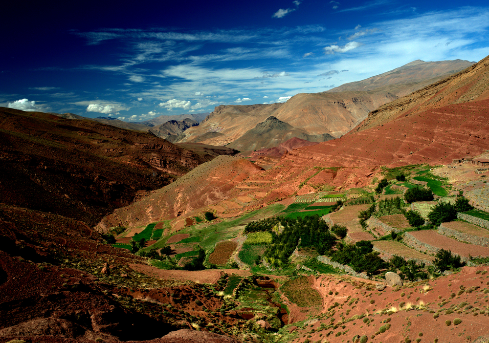 Clay dirt on the High Atlas Mountain range overlooking the valley with green fields below for a piece on the best places to visit in April