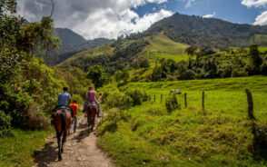 Two people on horseback in a lush valley on the Cocora trail in one of the best places to visit in Colombia