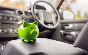 Green piggy bank on a car's console represents the cheapest way to rent a car