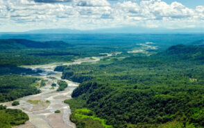 Aerial view of the Pastaza River Basin pictured with its winding shape in between countless green trees that stretch on for as far as the eye can see, taken during the best time to visit in the Amazon rainforest