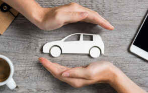 Hands curved around a white car cutout as a visual concept of should you get insurance for a rental car