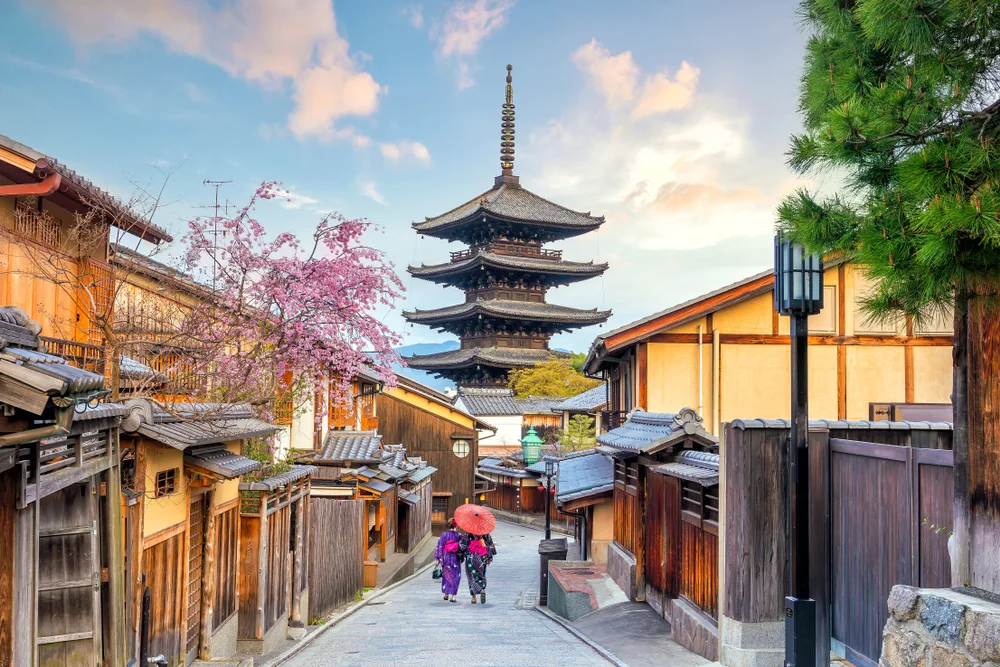 The Old Town area of Kyoto, pictured as one of the best places to go to in Asia, with two local woman with umbrellas walking down the street