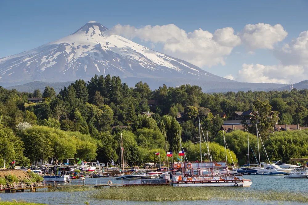 Giant Pucon volcano towering over the harbor with rickety boats pictured on the water