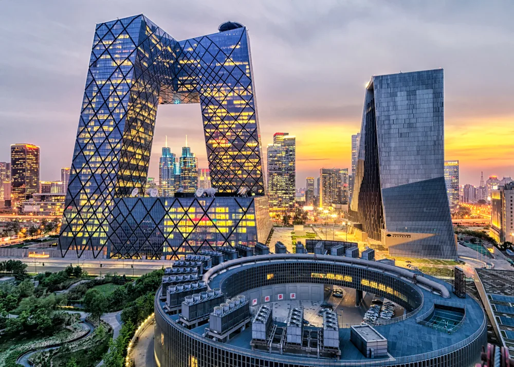 Giant M-shaped building towering over several other modern glass buildings with countless air conditioning units and modern gardens below in Beijing, one of the best places to visit in China