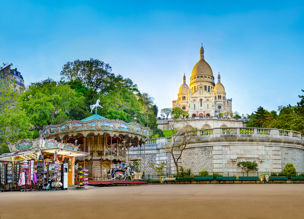 Sacre-Coeur towering over a merry-go-round and a merchandise shop in Paris