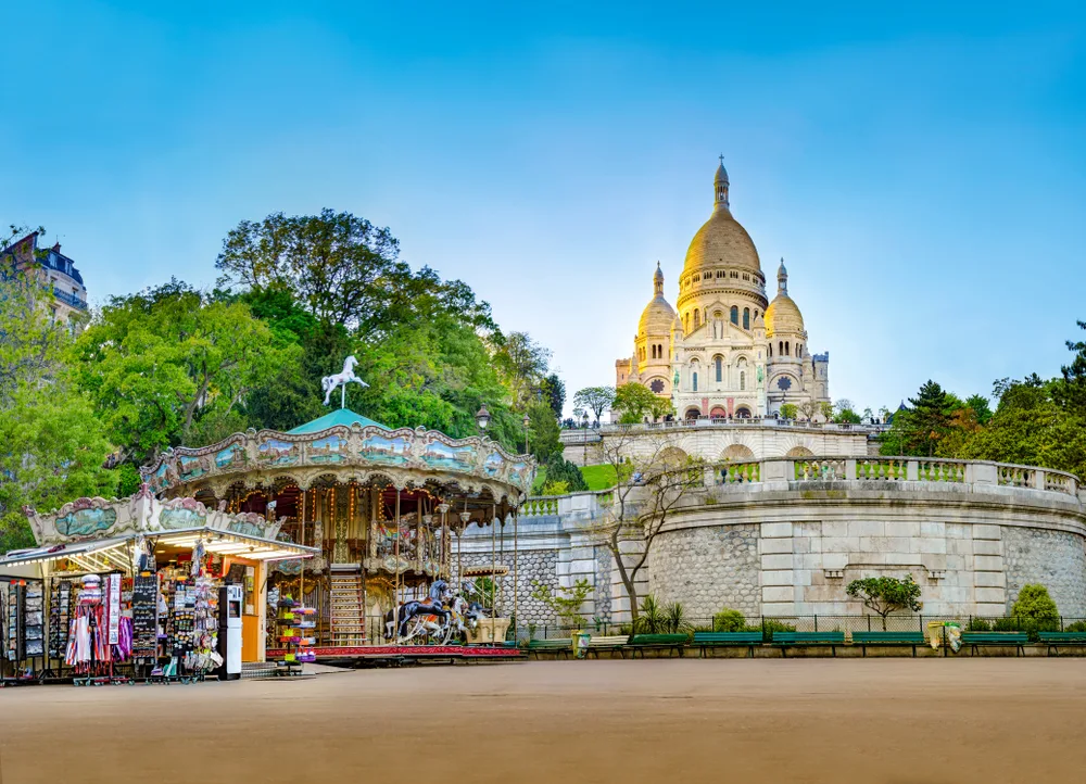 Sacre-Coeur towering over a merry-go-round and a merchandise shop in Paris