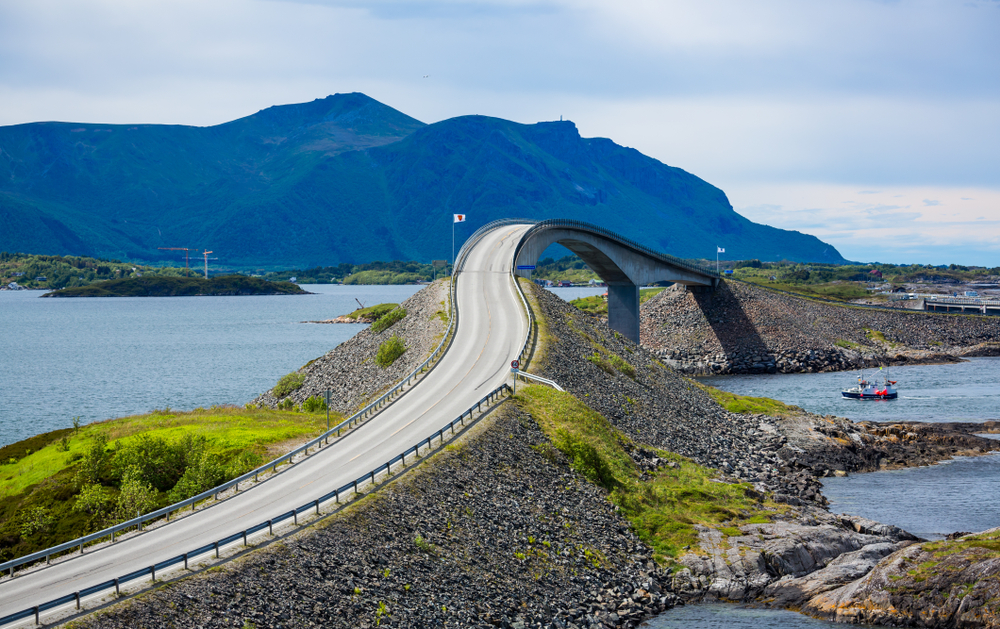Scenic view of the incredible and windy road with a tall bridge at Atlanterhavsveien, surrounded by tall mountains