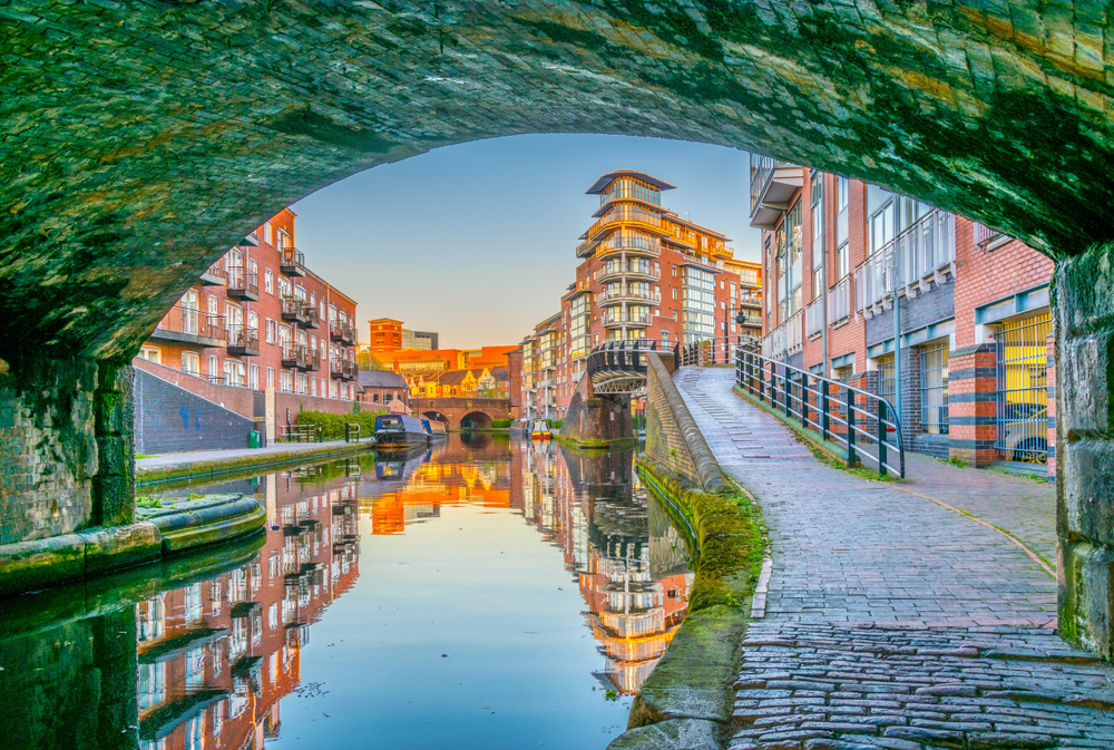 Historic old brick buildings towering over the canal, as seen from under a bridge, in Birmingham, one of the best places to visit in England