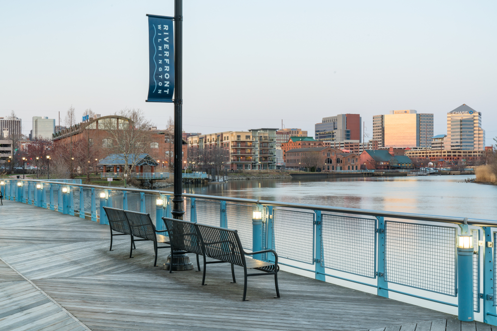 Metal park benches overlooking the water on a boardwalk in Wilmington, one of our top picks for places to visit in Delaware