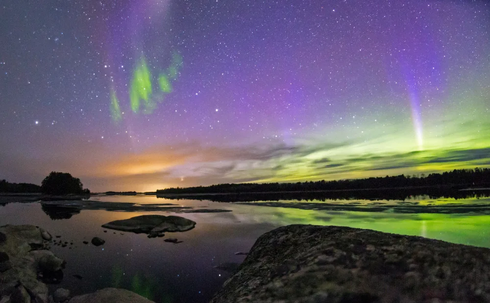 Night scene of one of the best places to visit in Minnesota, Voyageurs National Park, with the Northern Lights in the otherwise starry skyscape overhead