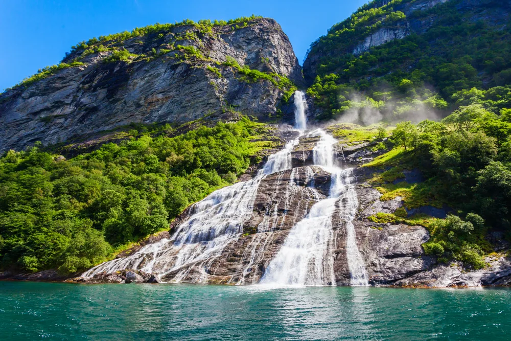 The Seven Sisters Waterfall in Geirangerfjord, one of our top picks for places to visit in Switzerland, with its gorgeous and wide stream plummeting into the bay below