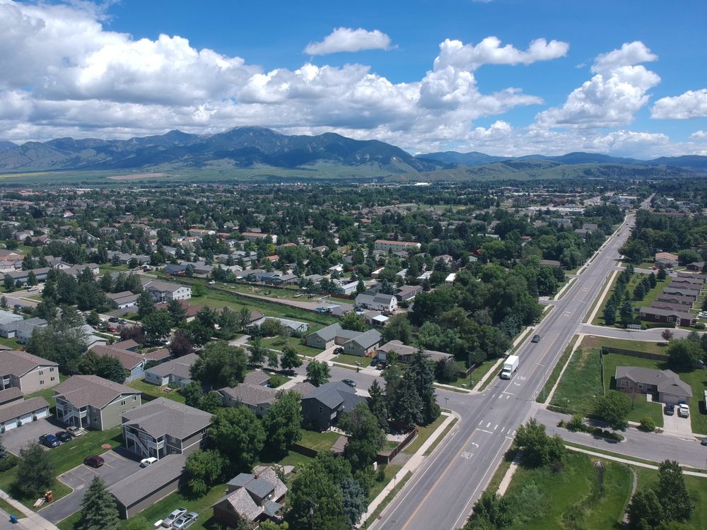 Drone photo of the valley town of Bozeman, one of the best places to stay in Montana, pictured with a mountain range in the background