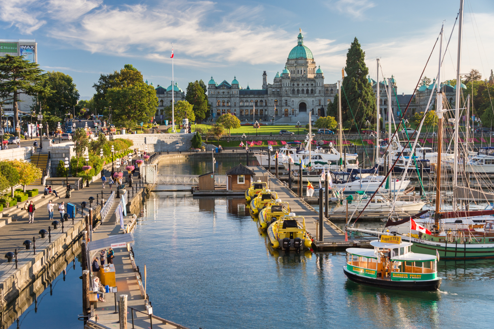 Quaint little harbor and the imposing Parliament building in Victoria, BC pictured on a nice day