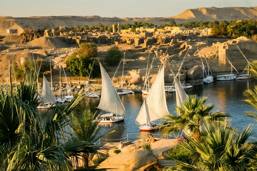 For a roundup of the best places to visit in Egypt, a few sailing boats float on the Nile River, just outside Aswan