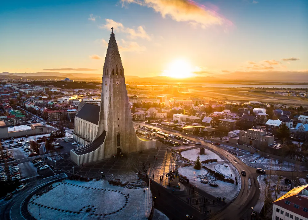 Reykjavik, one of the best places to visit in Iceland, pictured from the air with the sun setting over the Hallgrimskirkja church in the winter with snow all around