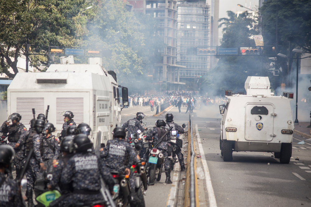 Riot with police and armored trucks pictured with smoke in the air
