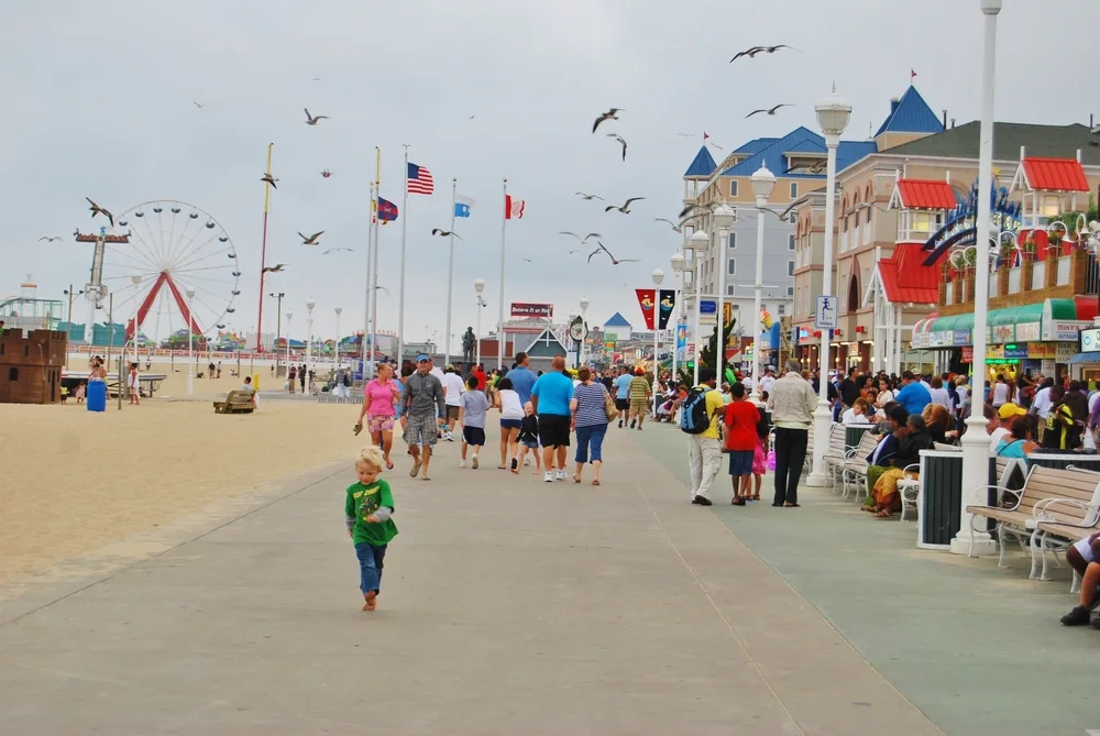 Crowded boardwalk in Ocean City with people walking along it and somewhat gloomy skies overhead