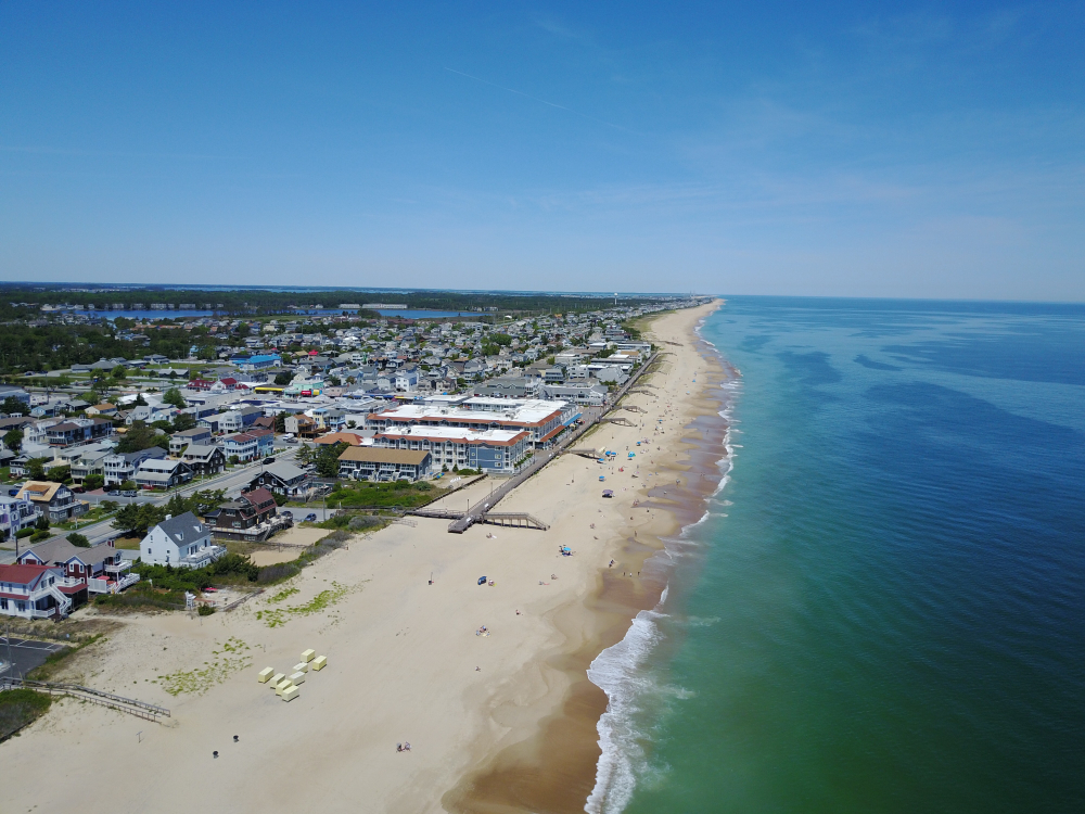 Aerial view of a nice summer day in one of our favorite places to visit in Delaware, Bethany Beach, with no clouds overhead and a nice, calm ocean below