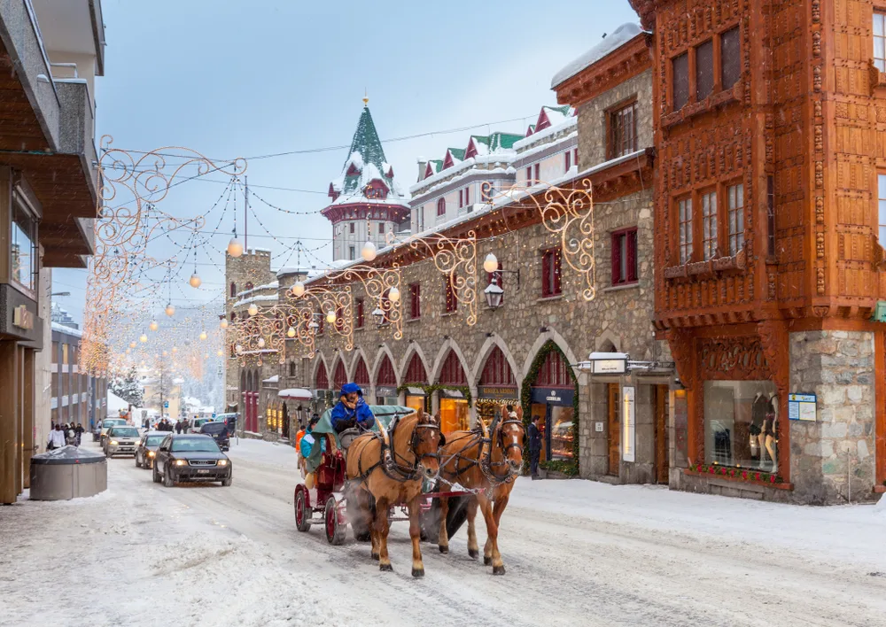 Winter view of one of Switzerland's best places to visit, St. Moritz, with people riding along the street in a horse-drawn carriage