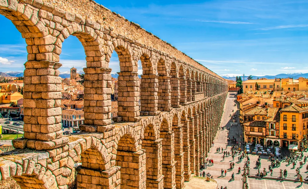 Ancient Roman aqueduct pictured running alongside the left side of the photo in the village of Segovia, one of the best places to visit in Spain