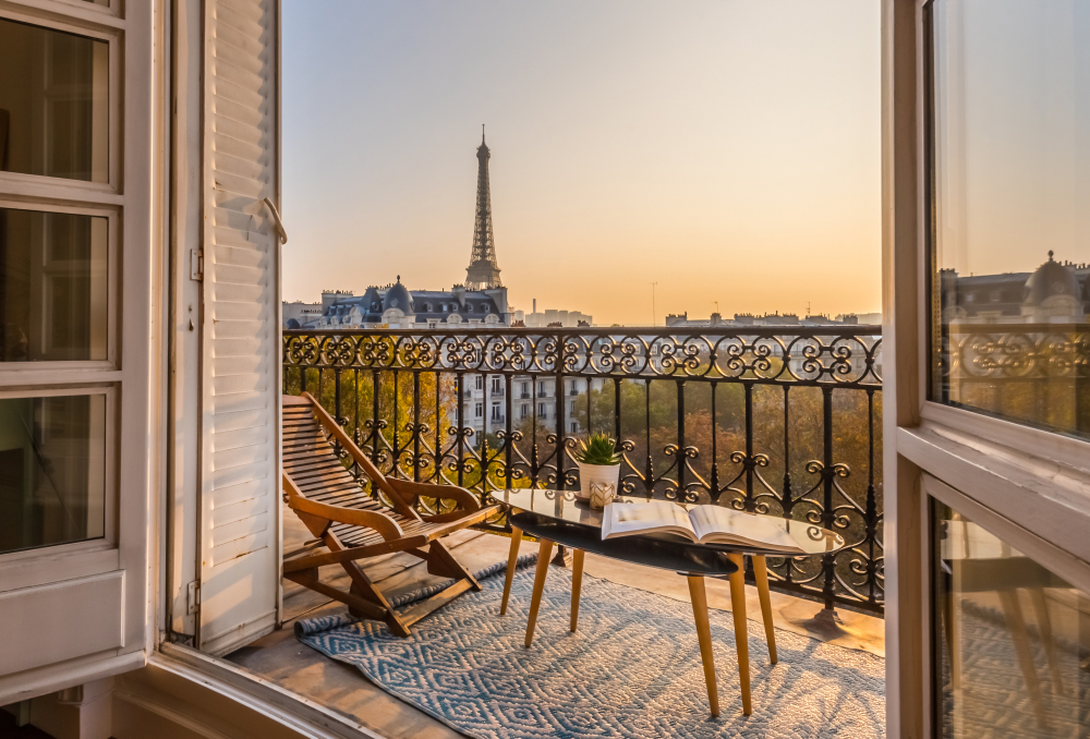Photo taken from the living room of a fancy hotel room with a view of the Eiffel Tower pictured with the patio window open in Paris, one of the best places to visit in Europe