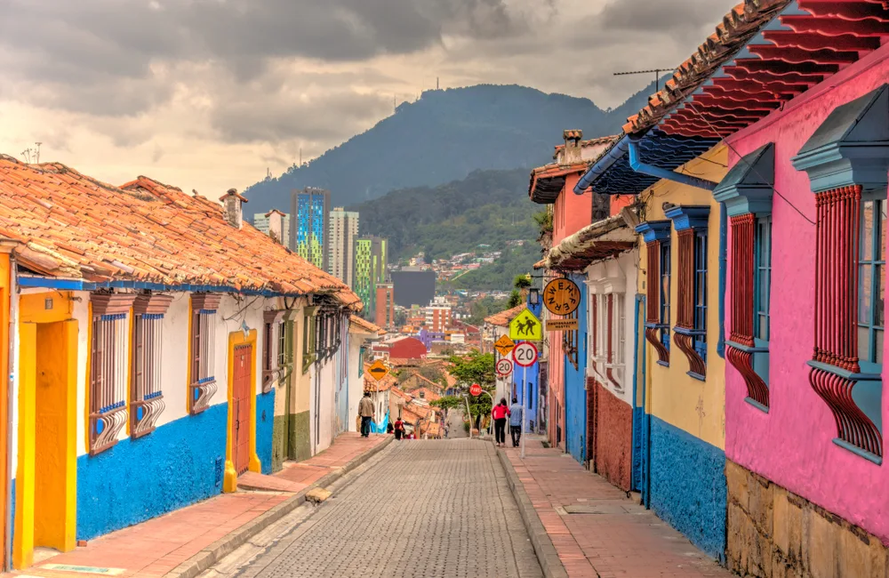 Narrow stone street between colorful buildings with a giant volcano in the background in Bogota, one of the best places to visit in Colombia
