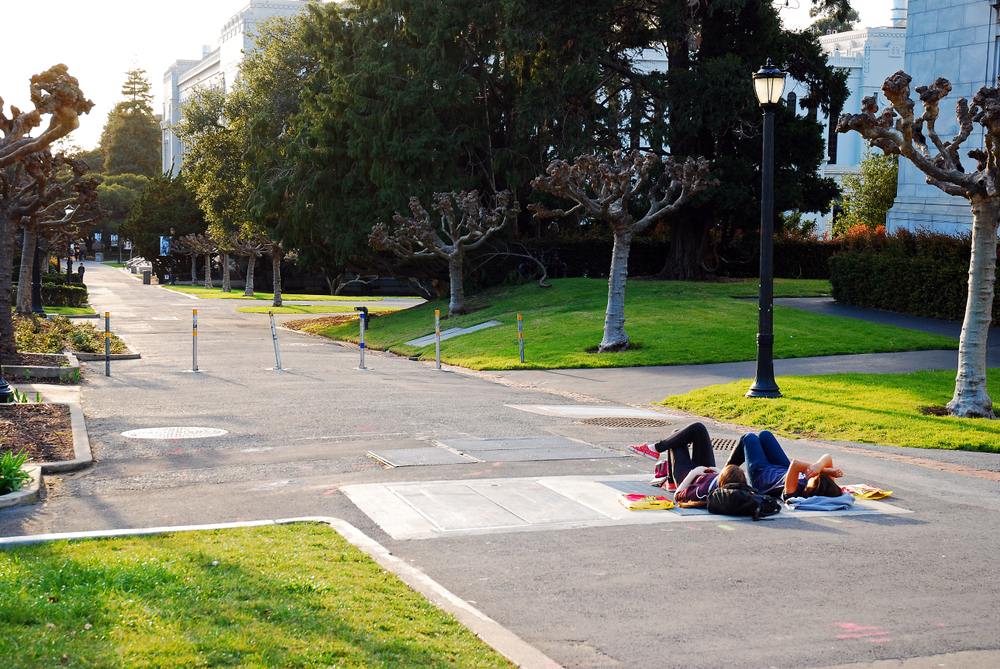 Two young college student lying on the cement walking path in Berkley for a piece on the best places to visit in the Bay Area