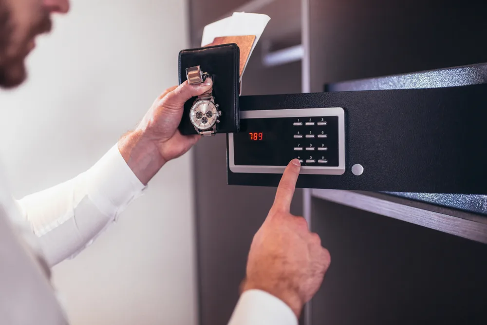 Man opens a safe in his hotel room to keep his watch and documents secure in the safest countries to visit right now