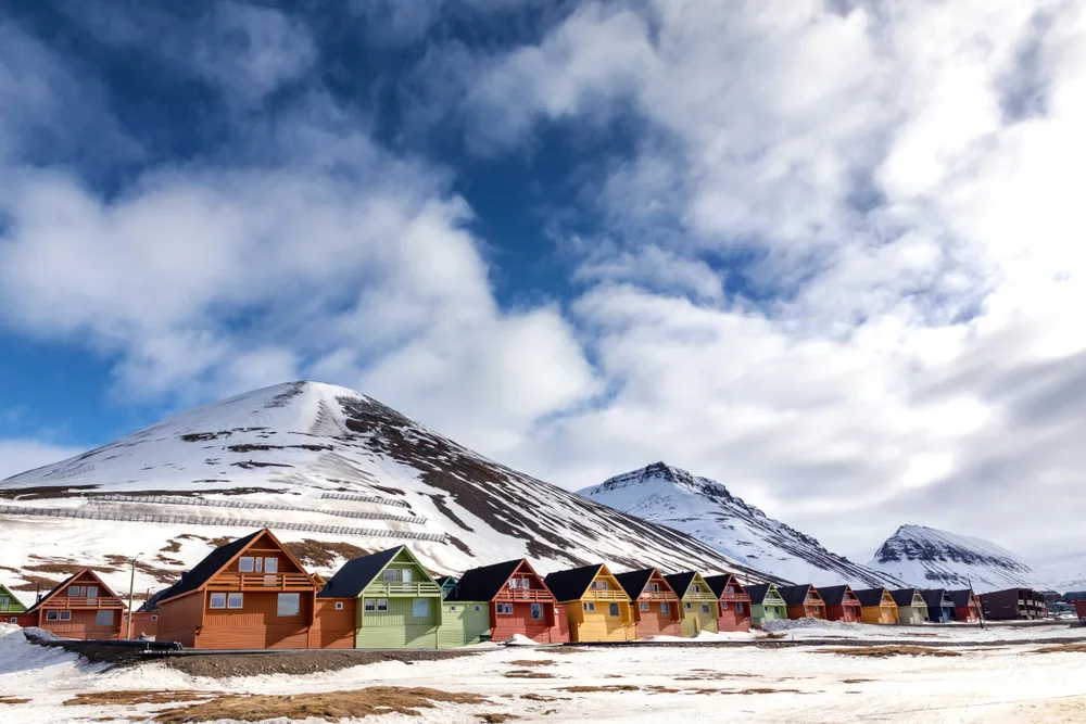 Row of colorful homes on the snow-capped mountain base in Svalbard