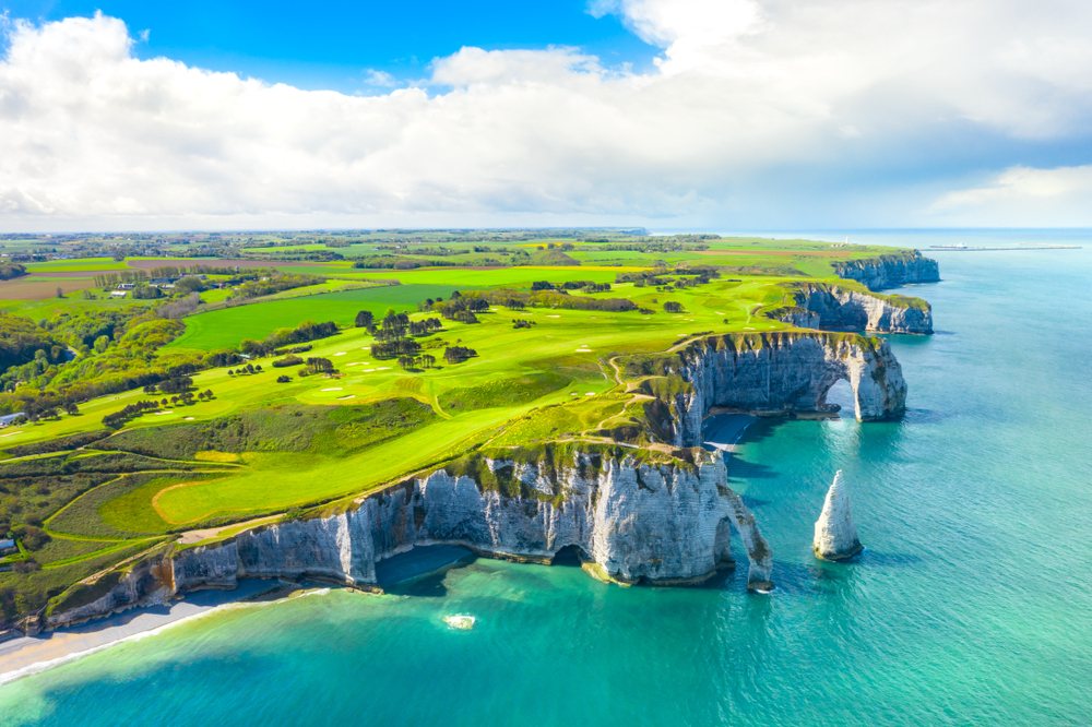 Picturesque aerial view of the lush green grass fields on the cliffside of Normandy, one of the best places to visit in France